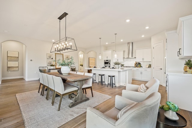 11182 N Via Ravenna Dr, Fresno, CA 93730 - dining area featuring light wood-type flooring, baseboards, arched walkways, and recessed lighting