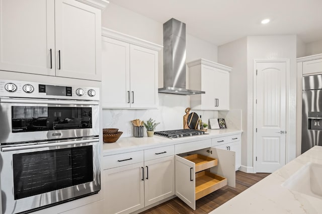 11182 N Via Ravenna Dr, Fresno, CA 93730 - kitchen featuring wall chimney exhaust hood, white cabinets, dark wood-style floors, decorative backsplash, and appliances with stainless steel finishes