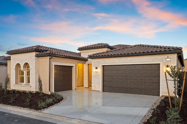 11182 N Via Ravenna Dr, Fresno, CA 93730 - mediterranean / spanish house featuring a tile roof, concrete driveway, stone siding, a garage, and stucco siding