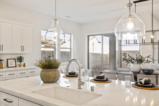 11182 N Via Ravenna Dr, Fresno, CA 93730 - kitchen featuring light stone counters, pendant lighting, white cabinetry, and a sink