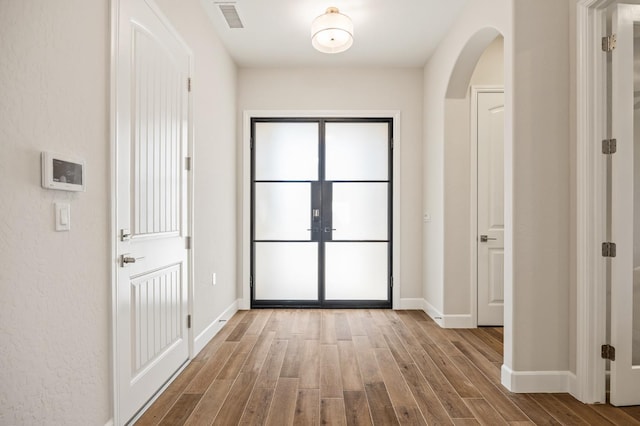 11182 N Via Ravenna Dr, Fresno, CA 93730 - doorway to outside featuring wood finished floors, visible vents, french doors, arched walkways, and baseboards