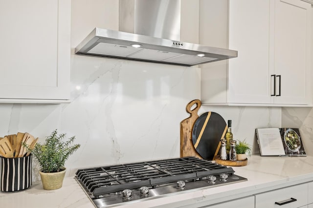 11182 N Via Ravenna Dr, Fresno, CA 93730 - kitchen featuring wall chimney range hood, tasteful backsplash, stainless steel gas cooktop, white cabinets, and light stone countertops