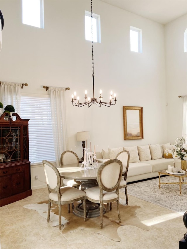 dining space featuring a towering ceiling and an inviting chandelier