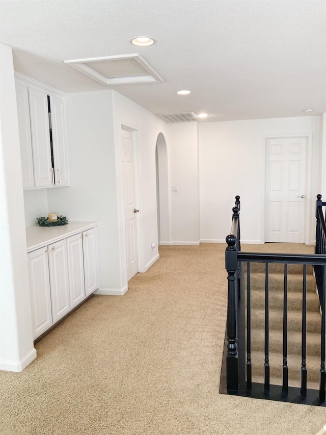 exercise room with arched walkways, light carpet, baseboards, visible vents, and recessed lighting