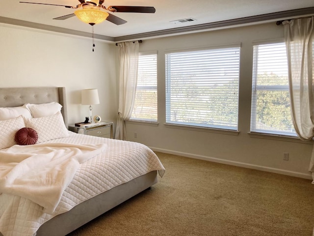 bedroom featuring carpet flooring, baseboards, visible vents, ceiling fan, and crown molding