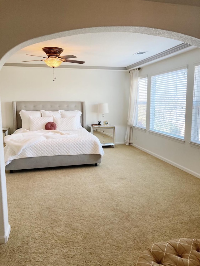 carpeted bedroom with baseboards, a ceiling fan, visible vents, and arched walkways