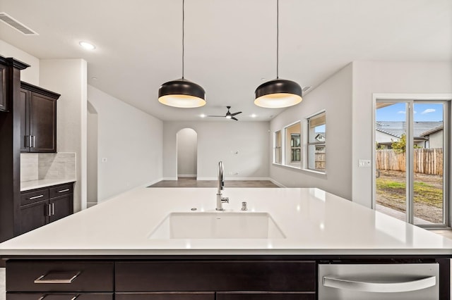 6294 E Miillie Dr, Fresno, CA 93727 - kitchen with arched walkways, light countertops, dark brown cabinetry, and a sink