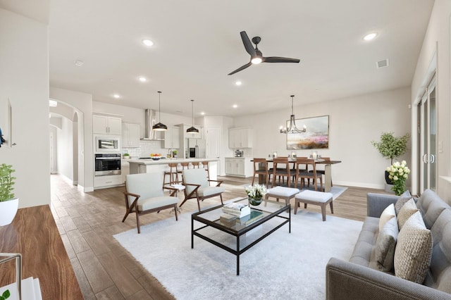 living room featuring recessed lighting, arched walkways, baseboards, light wood-style flooring, and ceiling fan