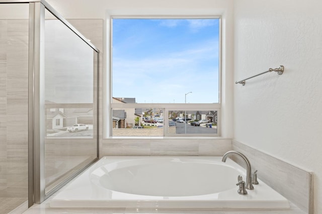 full bathroom with a textured wall and a garden tub
