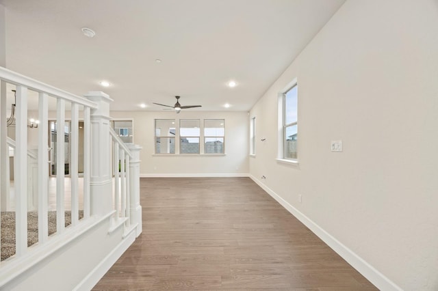 corridor with baseboards, wood finished floors, stairs, and recessed lighting