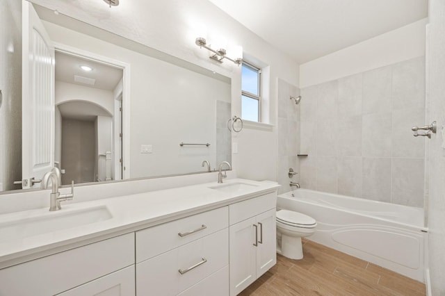 full bath featuring toilet, wood finished floors, a sink, and  shower combination