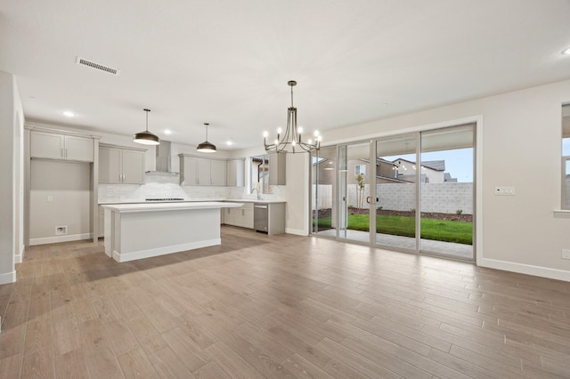kitchen with wall chimney exhaust hood, stainless steel dishwasher, visible vents, and a healthy amount of sunlight