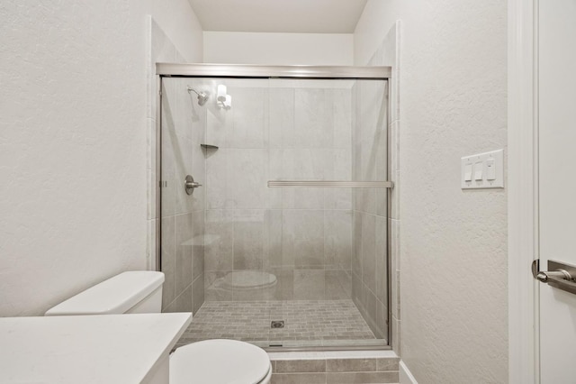 full bathroom featuring a stall shower, a textured wall, vanity, and toilet
