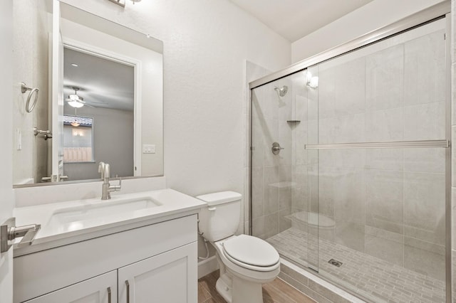 full bath with a shower stall, toilet, vanity, and ceiling fan