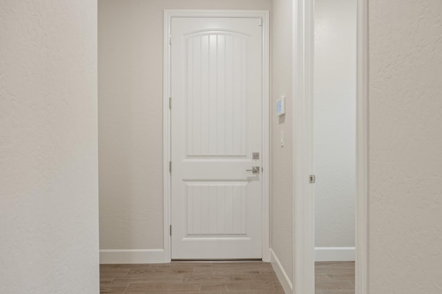 entryway featuring wood finished floors, baseboards, and a textured wall
