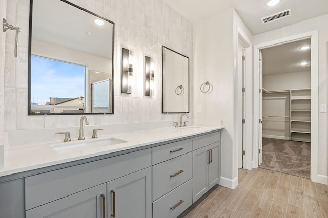 bathroom featuring a spacious closet, a sink, visible vents, and double vanity