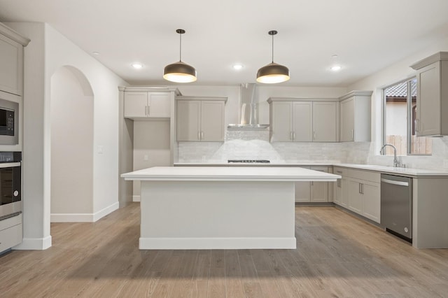 kitchen with stainless steel appliances, gray cabinets, tasteful backsplash, and wall chimney range hood