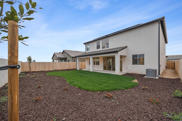 back of house featuring a fenced backyard, central AC unit, a patio area, a yard, and stucco siding