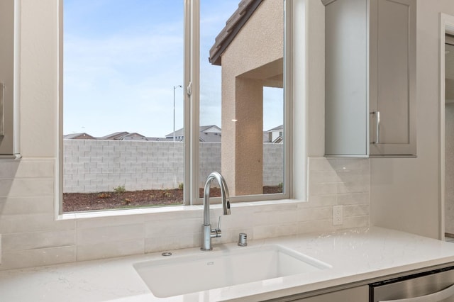 kitchen featuring dishwasher, decorative backsplash, gray cabinetry, and a sink