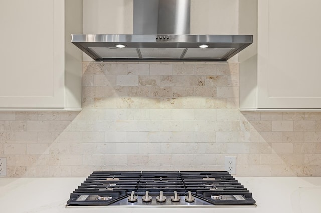 interior details with stainless steel gas stovetop, light countertops, exhaust hood, and tasteful backsplash