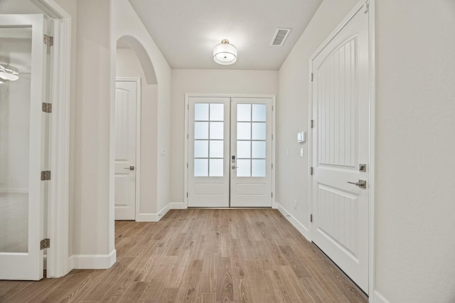 doorway to outside with visible vents, french doors, arched walkways, light wood-type flooring, and baseboards