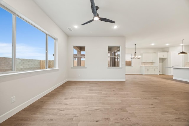 unfurnished living room featuring recessed lighting, light wood finished floors, baseboards, and ceiling fan with notable chandelier