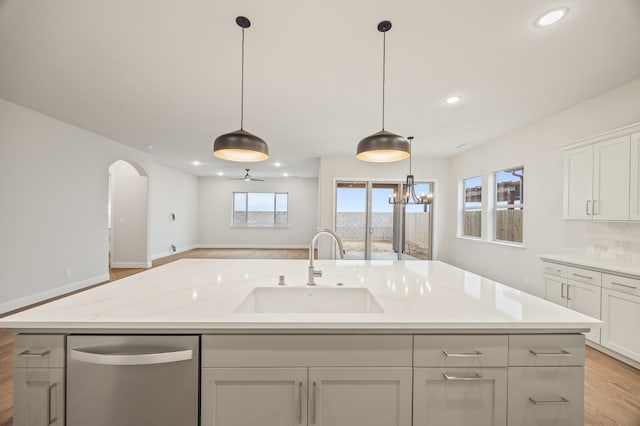kitchen featuring stainless steel dishwasher, a sink, an island with sink, light wood-style floors, and recessed lighting