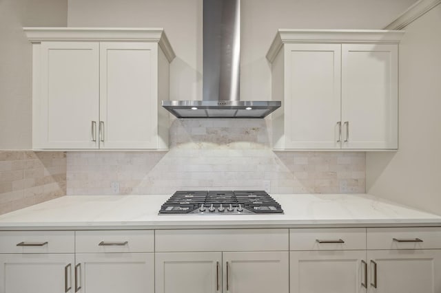 kitchen featuring stainless steel gas cooktop, wall chimney range hood, decorative backsplash, and white cabinetry