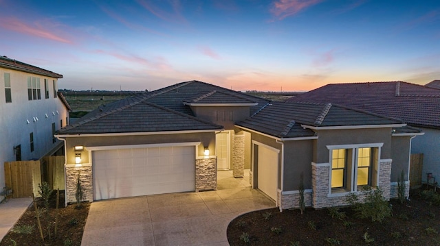 view of front of property with stucco siding, a tile roof, stone siding, and a garage