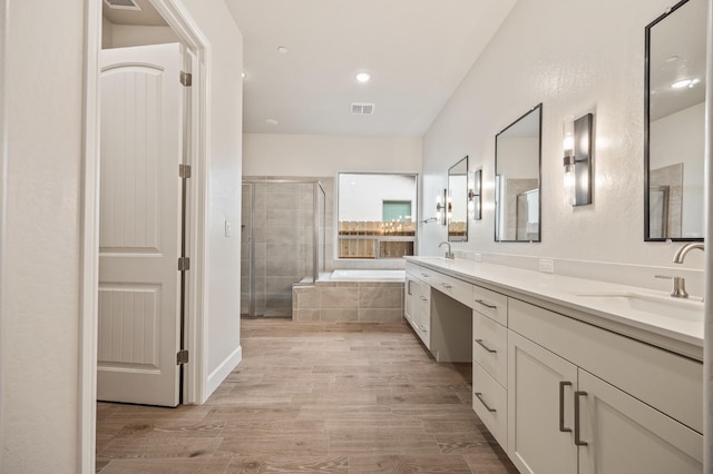 bathroom featuring a bath, a sink, double vanity, a stall shower, and visible vents
