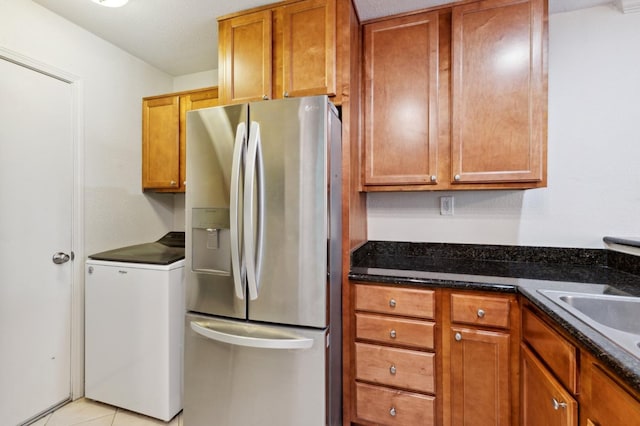 7178 N Fruit Ave Unit 132, Fresno, CA 93711 - kitchen featuring dark stone countertops, a sink, refrigerator, brown cabinetry, and stainless steel refrigerator with ice dispenser