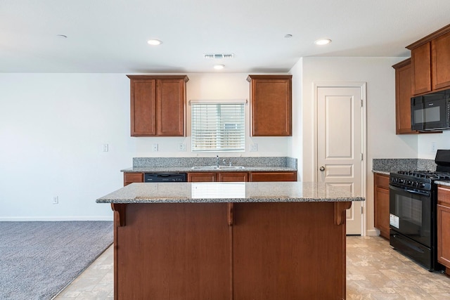 kitchen featuring black appliances, a sink, light stone countertops, a kitchen island, and light carpet