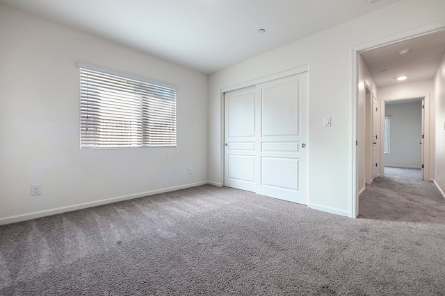 unfurnished bedroom featuring carpet, baseboards, and a closet