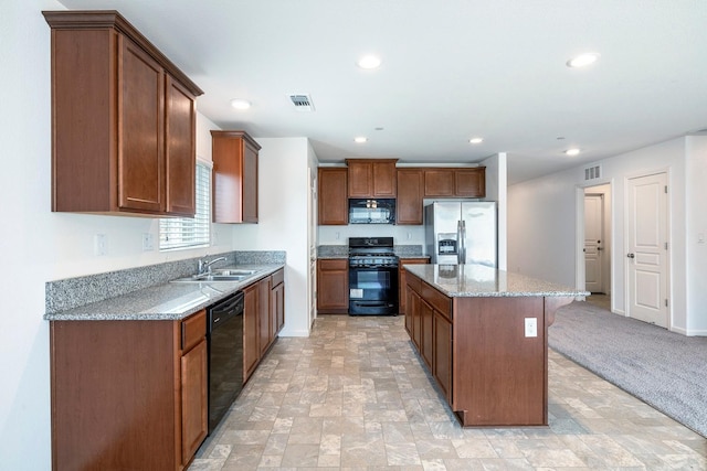 kitchen with black appliances, a sink, a center island, light stone countertops, and a breakfast bar area