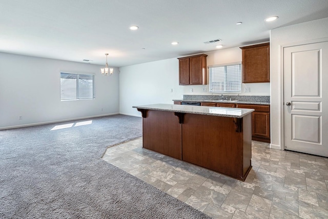 kitchen with a kitchen island, a chandelier, a sink, a breakfast bar, and light stone counters