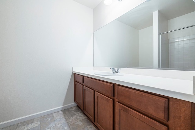 full bath with baseboards, vanity, and stone finish floors