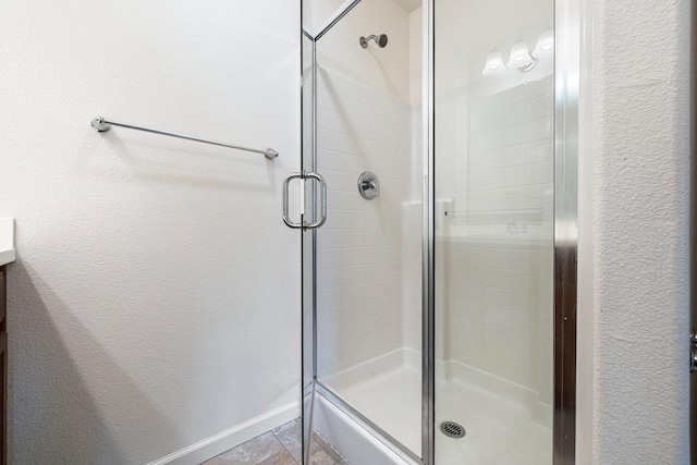 full bathroom with a stall shower and baseboards