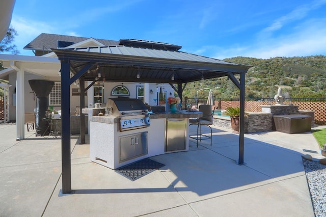 view of patio / terrace featuring fence, a gazebo, area for grilling, an outdoor bar, and a grill