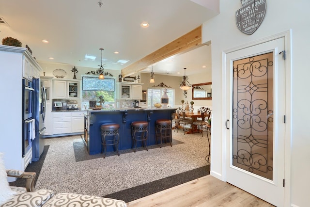 kitchen featuring white cabinets, recessed lighting, a breakfast bar, and a kitchen island