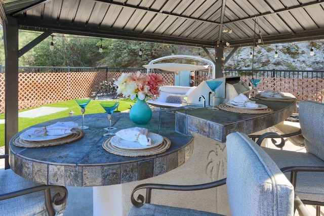 view of patio with a gazebo, fence, and outdoor dry bar