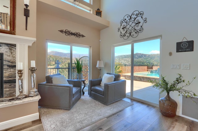 living room featuring plenty of natural light, a mountain view, a towering ceiling, and wood finished floors