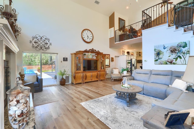 living area featuring high vaulted ceiling, stairs, wood finished floors, and visible vents