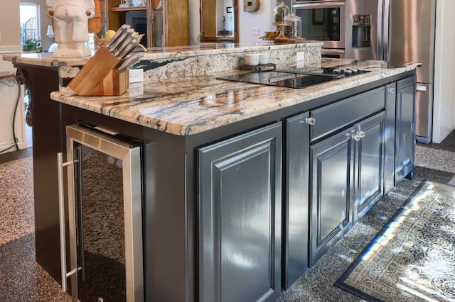 kitchen featuring a center island, appliances with stainless steel finishes, wine cooler, and light stone countertops