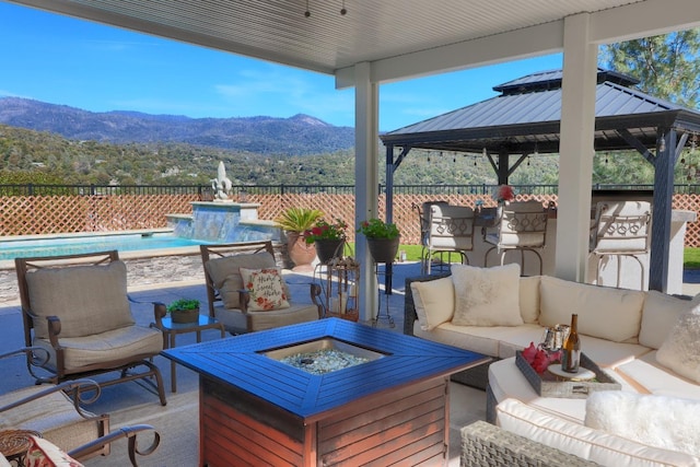 exterior space with a gazebo, a fenced in pool, a mountain view, and an outdoor living space with a fire pit