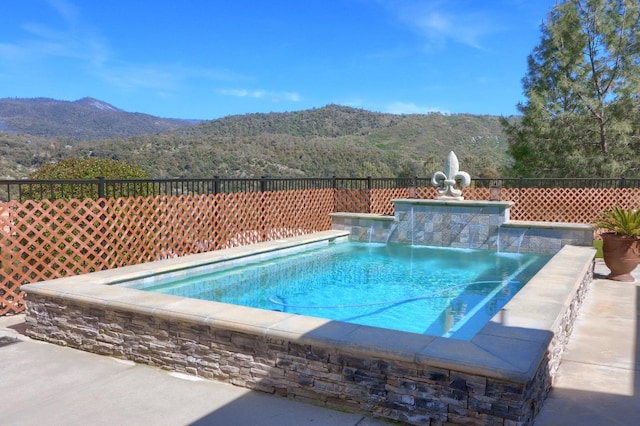 view of pool with fence, a mountain view, and a pool