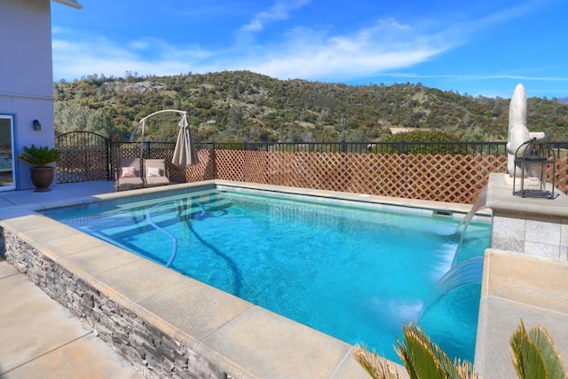 view of swimming pool with a fenced in pool, fence, a mountain view, and a wooded view