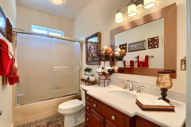 full bathroom with vanity, bath / shower combo with glass door, and toilet