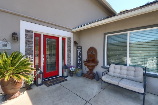 property entrance with stucco siding, a patio area, and stone siding