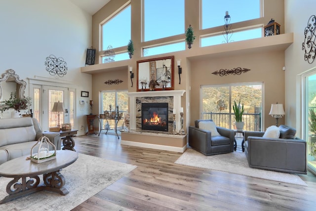 living area featuring a glass covered fireplace, a high ceiling, and wood finished floors