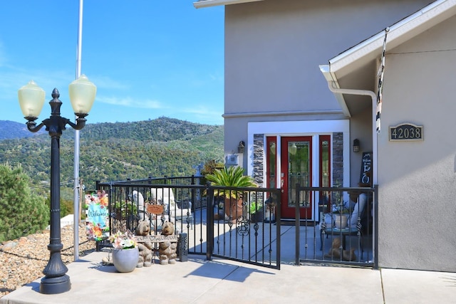 property entrance with a forest view, a balcony, a mountain view, and stucco siding